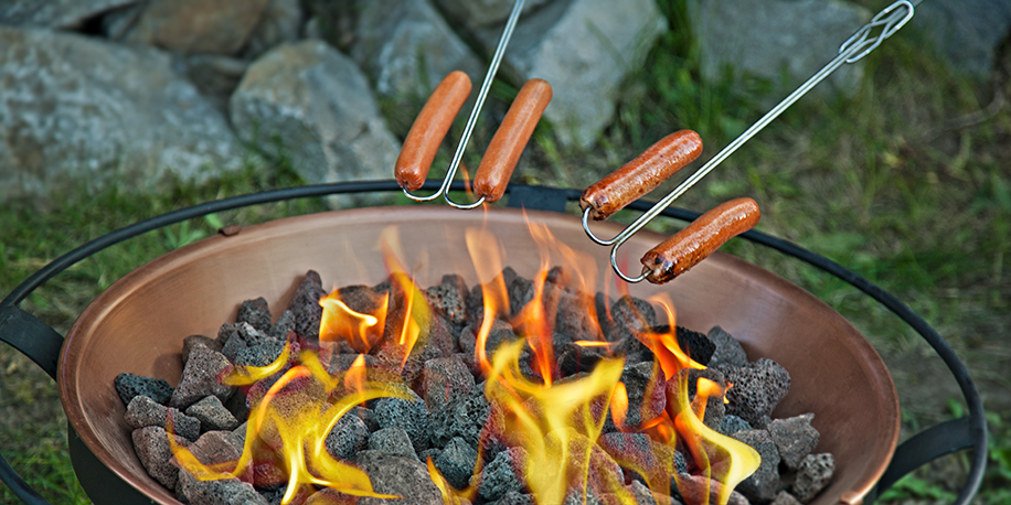 Hot dogs roasting over propane fire pit