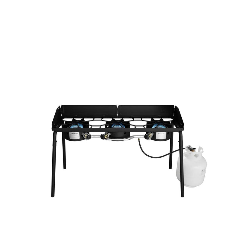 Load image into Gallery viewer, The Camp Chef Explorer is a black, three-burner outdoor stove with four legs and a metal wind guard around the burners. Shown connected to a white propane tank, it offers versatile outdoor cooking on any adventure.