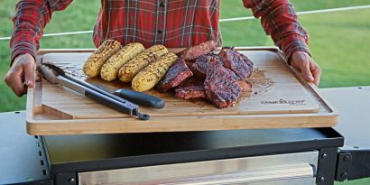 Bamboo cutting board holding steak and corn