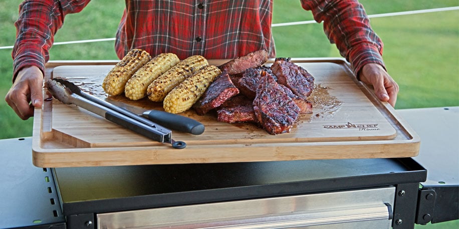 Bamboo cutting board holding steak and corn