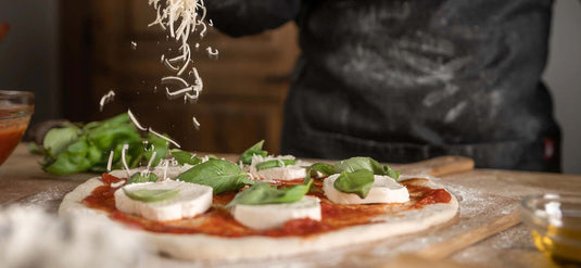 cheese getting sprinkled on a pizza