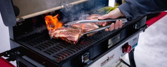 Man grilling steaks on a stove