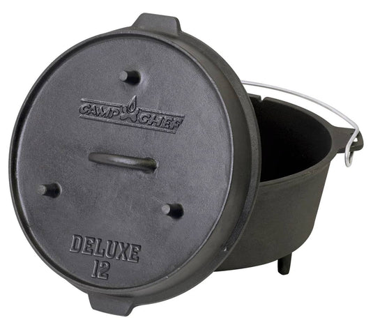 The Camp Chef Deluxe Dutch Oven is a black cast iron pot with three short legs, a metal handle, and a partially open lid leaning against it.