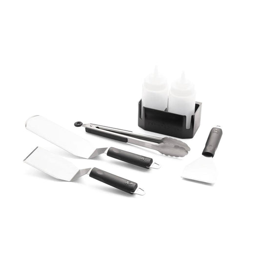 The Camp Chef Griddle Essentials Kit includes two spatulas, tongs, a scraper, two squeeze bottles, and a black caddy—all arranged on a white background for your flat top grill needs.