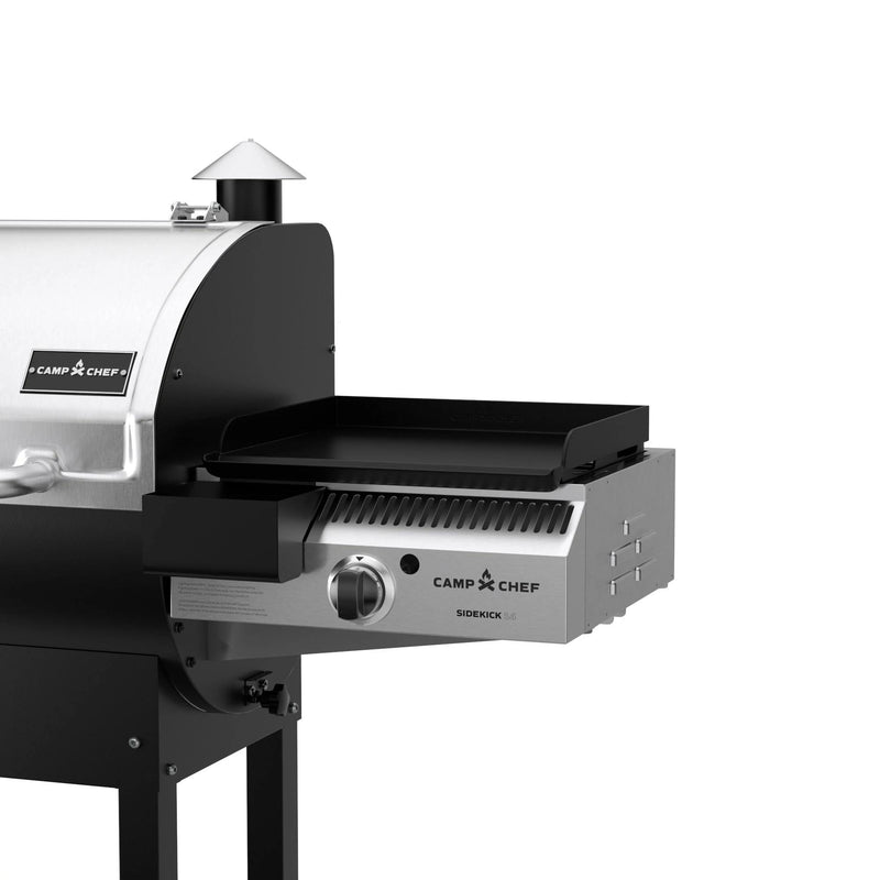 Load image into Gallery viewer, A close-up of the Camp Chef Sidekicks, a versatile pellet grill accessory with stainless steel and black accents, highlights the propane burner on the right side of this flat-top griddle attachment.
