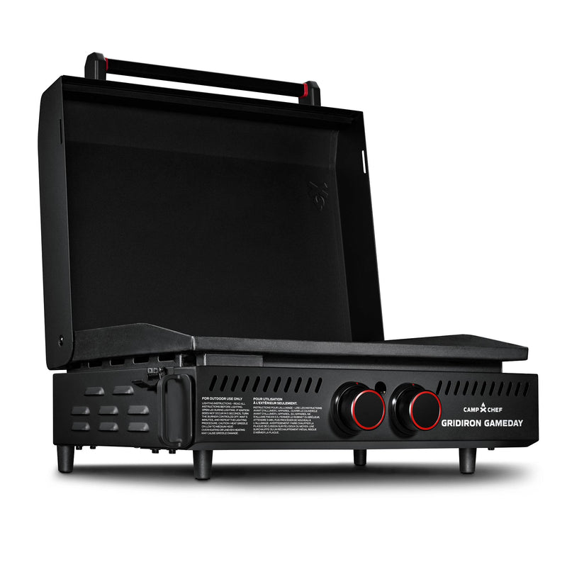 Load image into Gallery viewer, The Camp Chef Gridiron Gameday is a portable black tabletop gas grill featuring a large cooking surface, hinged lid, two red-accented control knobs, and sturdy short legs—ideal for tailgates and outdoor cooking.

