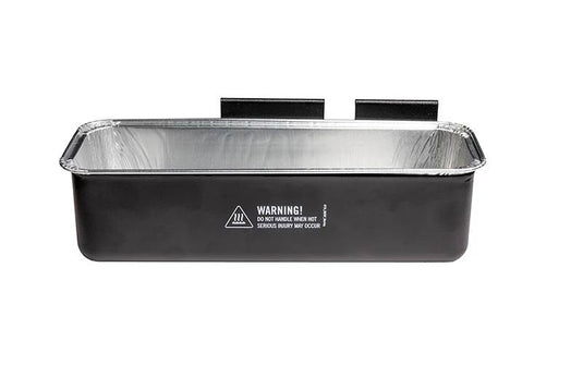 The Camp Chef Disposable Grease Cup Liner (5-Pk) is a black rectangular metal tray with a silver interior, two rear mounting brackets, and a front hot surface warning label—perfect for catching grease from your flat top griddle.