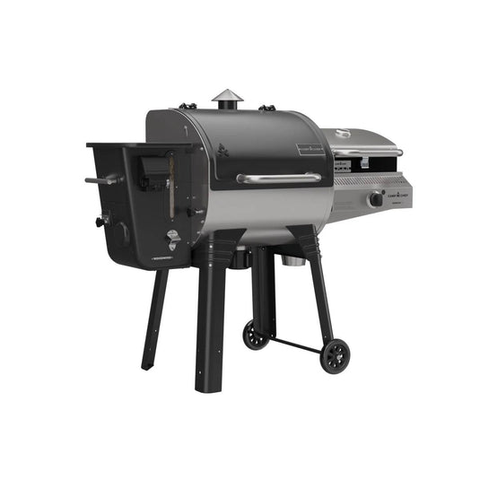 The Camp Chef Woodwind 24 is a black and silver outdoor pellet grill and smoker with a WIFI controller, chimney, control panel, side shelf, and sturdy wheeled legs for easy portability.