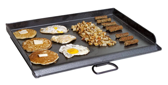 The Camp Chef Griddles 16 shows pancakes with butter, sunny-side-up eggs, diced browned potatoes, and sausage links neatly arranged in rows on its flat top griddle.