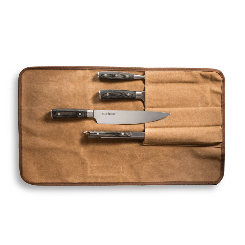 Load image into Gallery viewer, The Camp Chef 4 Piece Carving Set is shown in a brown canvas knife roll pouch, partially open to reveal three stainless steel knives and a peeler with black handles, each neatly arranged in separate slots.
