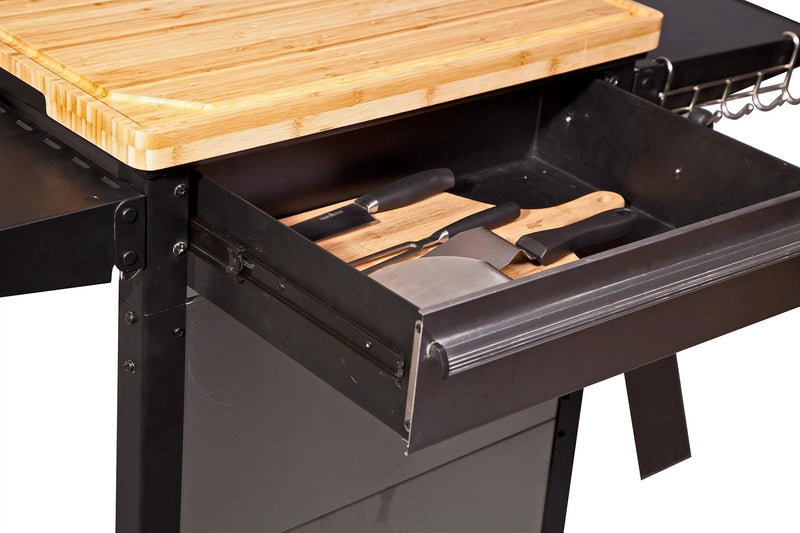 Load image into Gallery viewer, A close-up of the Camp Chef Patio Cart shows an open drawer with several kitchen knives beneath a wooden cutting board on top.
