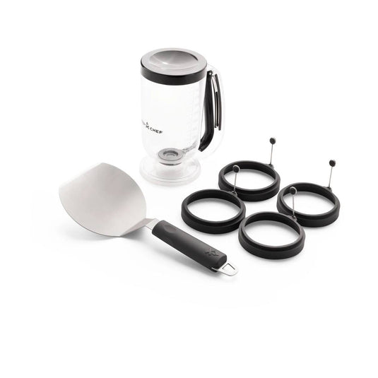 The Camp Chef Breakfast Kit includes a clear batter dispenser with a black lid and handle, a stainless steel spatula with black handle, and four egg rings for perfectly round eggs.