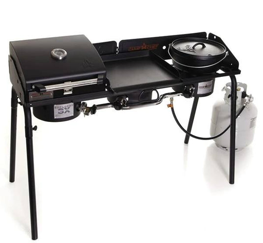 The Camp Chef Explorer is a portable outdoor stove with three sections: a grill with lid and temperature gauge, a central flat griddle, and a right-side pot burner, all fueled by propane for versatile outdoor cooking.