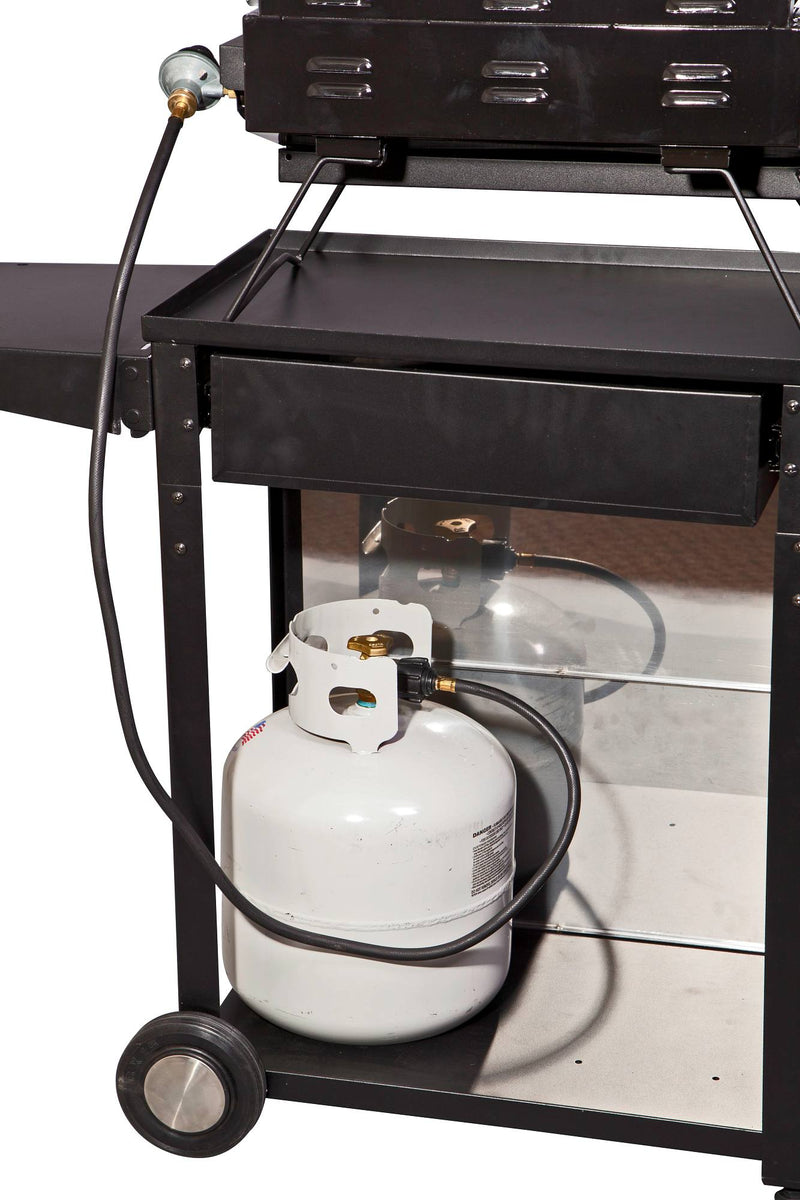Load image into Gallery viewer, A white propane tank is connected by hose to a black outdoor grill on the lower shelf of the Camp Chef Patio Cart, with one wheel and a side shelf of the cart also visible.
