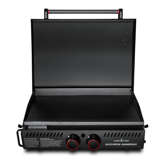 The Camp Chef Gridiron Gameday is a black portable griddle with an open lid, two front control knobs, and a spacious cooking surface—ideal for outdoor cooking or tailgating.