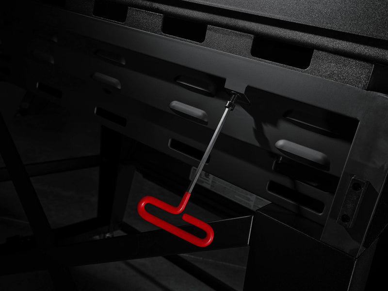 Load image into Gallery viewer, A close-up of the Camp Chef Gridiron 36 showcases a red-handled tool in the side slot, highlighted against the sleek black griddle for convenient clean-up after even heating.
