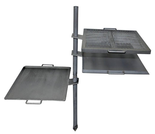 The Camp Chef Mountain Man Grill is a metal outdoor cooking system with a vertical pole and three adjustable surfaces—a griddle, solid tray, and over-fire grill—each with handles for easy campfire cooking versatility.