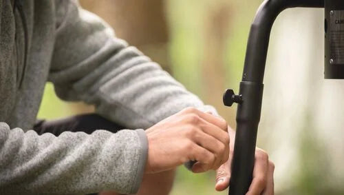 Person adjusting a bike pump with a blurred natural background