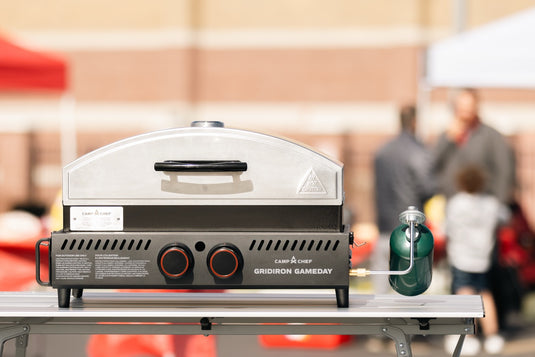 Portable grill on a stand with people in the background
