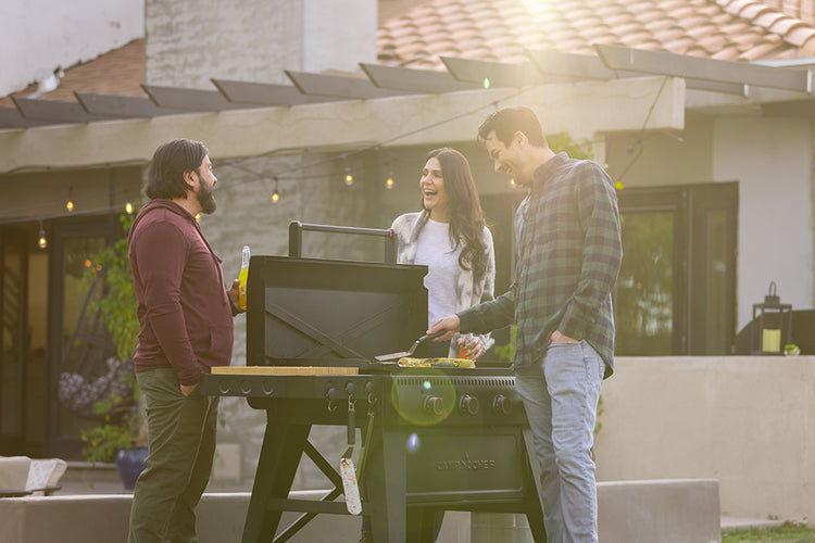 Three people around a barbecue grill in a backyard setting