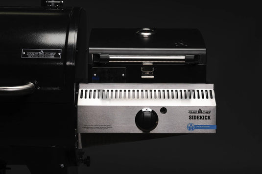 A close-up of a Camp Chef Sidekicks accessory shows the control knob, branding, and part of the main grill against a dark background.