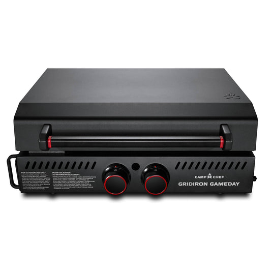 The Camp Chef Gridiron Gameday grill features a black finish, closed lid, dual control knobs, and front ventilation slits—ideal for outdoor cooking and portable tailgates.