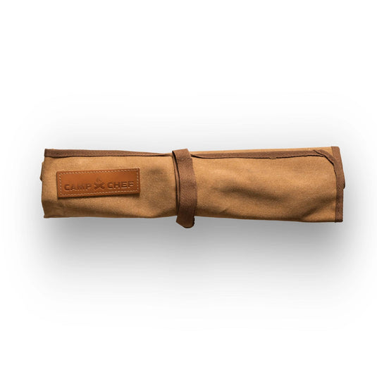 The Camp Chef 4 Piece Carving Set features a tan canvas knife roll with a leather Camp Chef patch and strap, ideal for storing stainless steel knives. Displayed on a white background.
