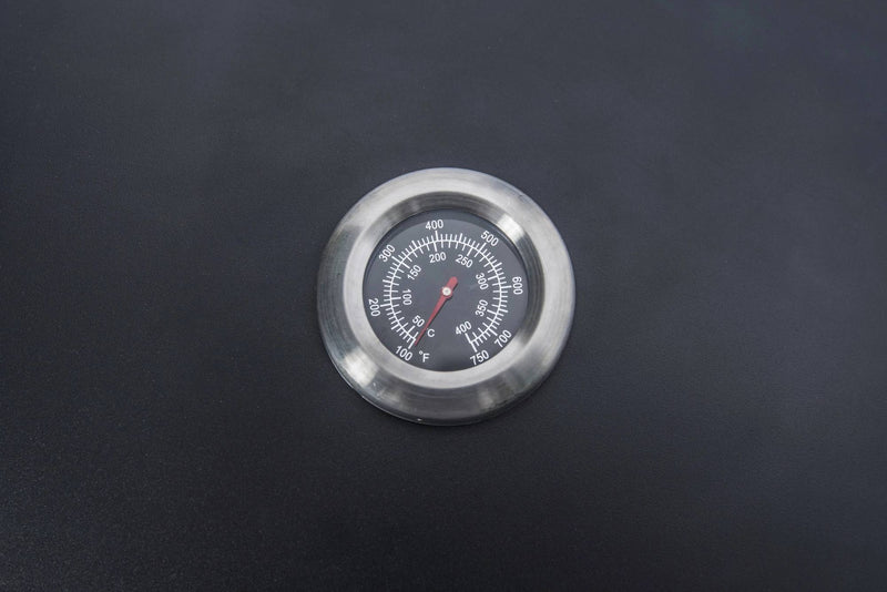Load image into Gallery viewer, A Camp Chef BBQ Grill Boxes 14 thermometer, featuring a black face with white markings for Celsius and Fahrenheit, rests atop the smooth cast iron grilling surface.
