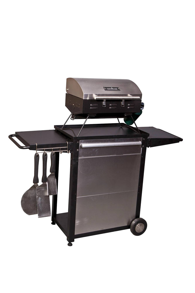 Load image into Gallery viewer, The Camp Chef Patio Cart is a stainless steel outdoor gas grill with a closed lid, side shelves, two wheels, and barbecue tools hanging on the left—ideal as an outdoor kitchen cart—shown isolated on a white background.
