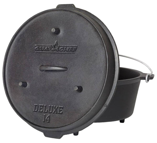 A black cast iron Deluxe Dutch Oven by Camp Chef features a handled lid labeled "Deluxe 14" and a metal handle, with the lid leaning against the pot.