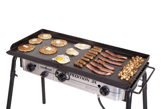 The Camp Chef Griddles 16, a large flat top with three control knobs and four sturdy legs, cooks pancakes, eggs, sausage links, bacon, and diced potatoes in neat rows—ideal for outdoor breakfasts.